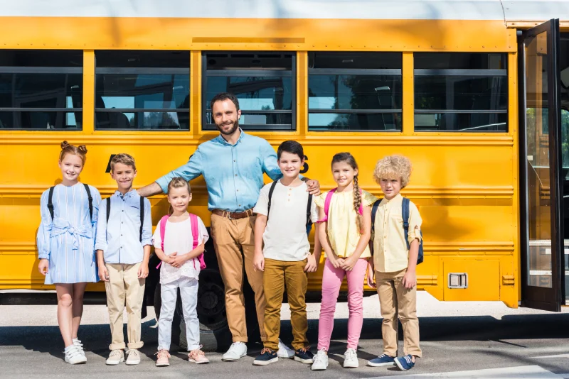 About Transpo Bus Service LLC schoolchildren and teacher standing together in front of school bus and looking at camera